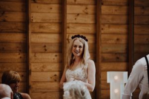 Bride giving speech with a red rose flower crown and lace detail on dress