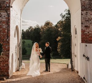 Bride & Groom walking under arch | UK luxury wedding