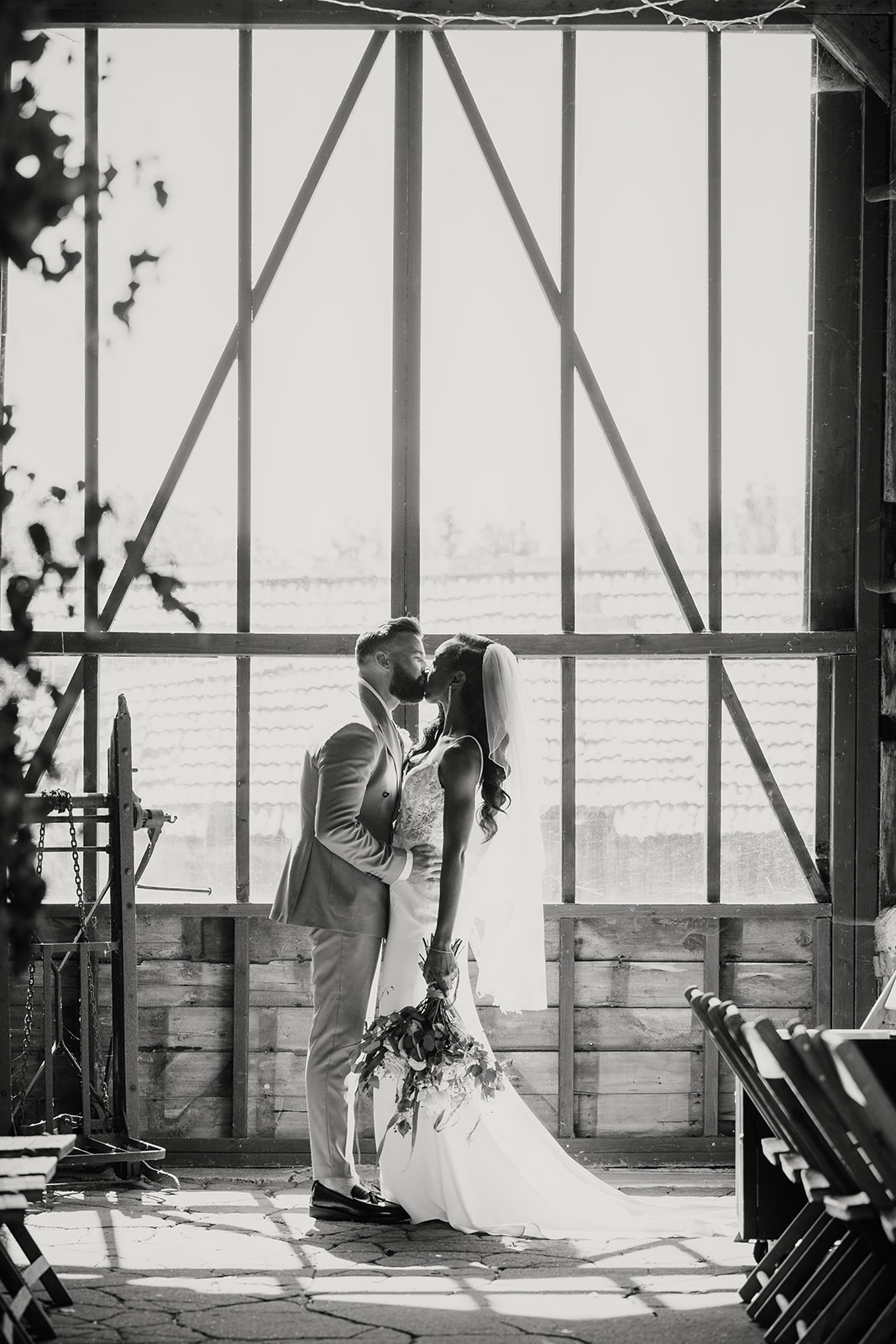 Bride & Groom Sharing a Gentle Kiss in Front of a Large Window on Their Wedding Day, Captured in a Calm Moment Supported by Hayley, Freelance Wedding & Event Coordinator for Catering Teams