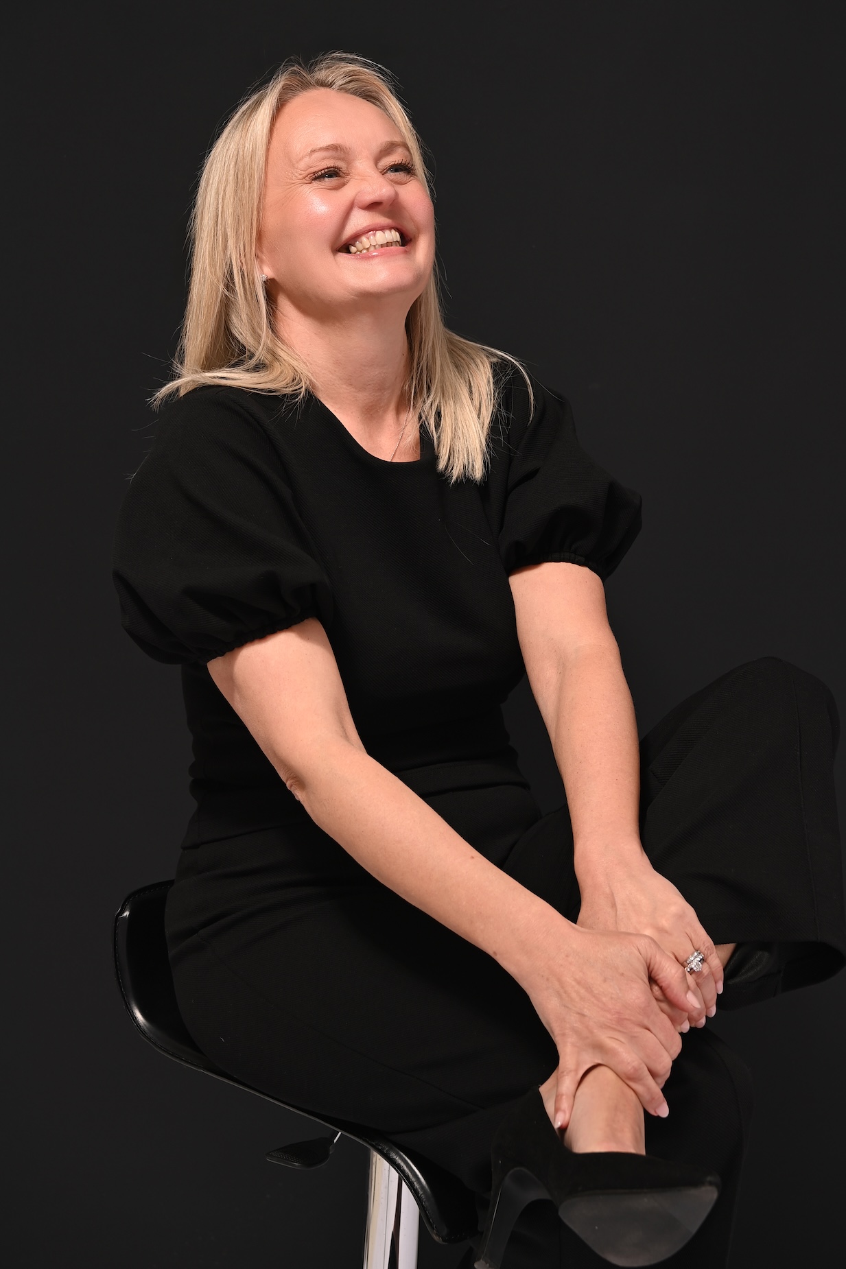 Hayley Wedding & Event Coordinator Hayley Sitting on a Stool, Laughing, Captured in a Relaxed Moment as a Freelance Wedding & Event Coordinator